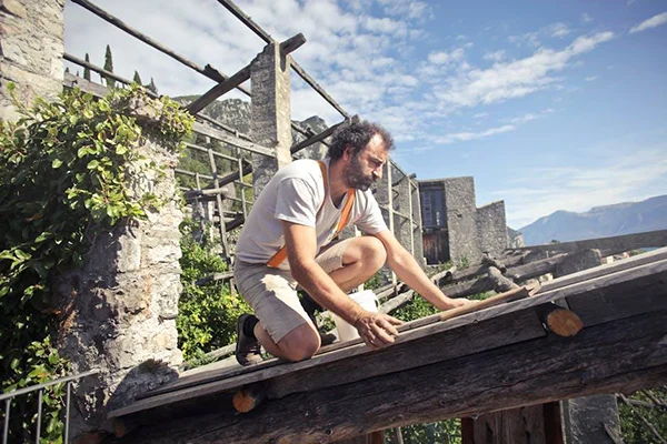 focused-man-building-roof-of-wooden-construction