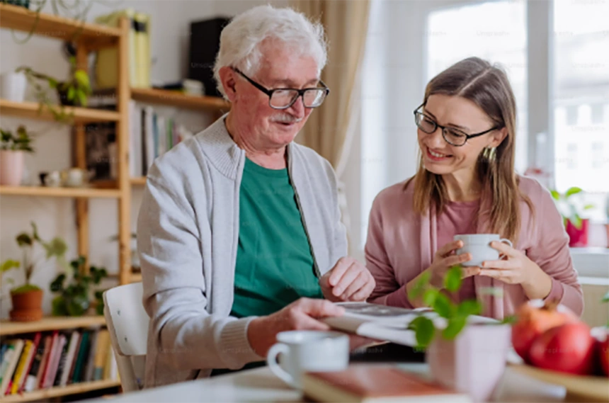 Adult daughter and elderly father looking at paperwork together at a kitchen table