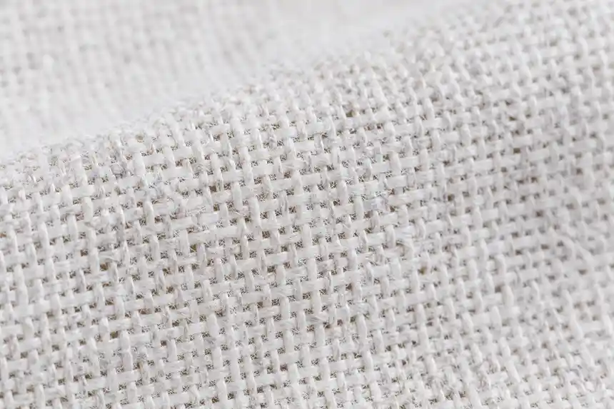 Close-up of woven cotton sheet fabric showing individual warp and weft threads