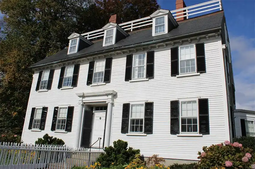A New England home showing its roof and siding surrounded by autumn