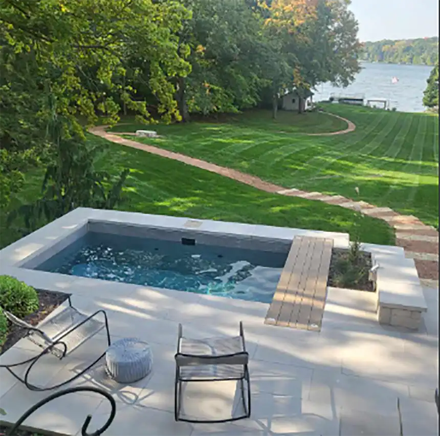 Backyard swimming pool under construction beside a residential home, with fencing, patio space, and landscaped yard.